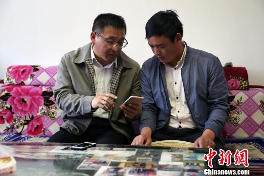 资料图为青海省海东市互助土族自治县班彦村第一书记袁光平正在用手机为当地土族村民吕根登牛肉演示“光e宝”功能。 罗云鹏 摄