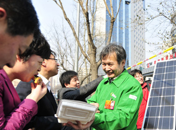 黄鸣为两会代表及过往群众烤制太阳能地瓜